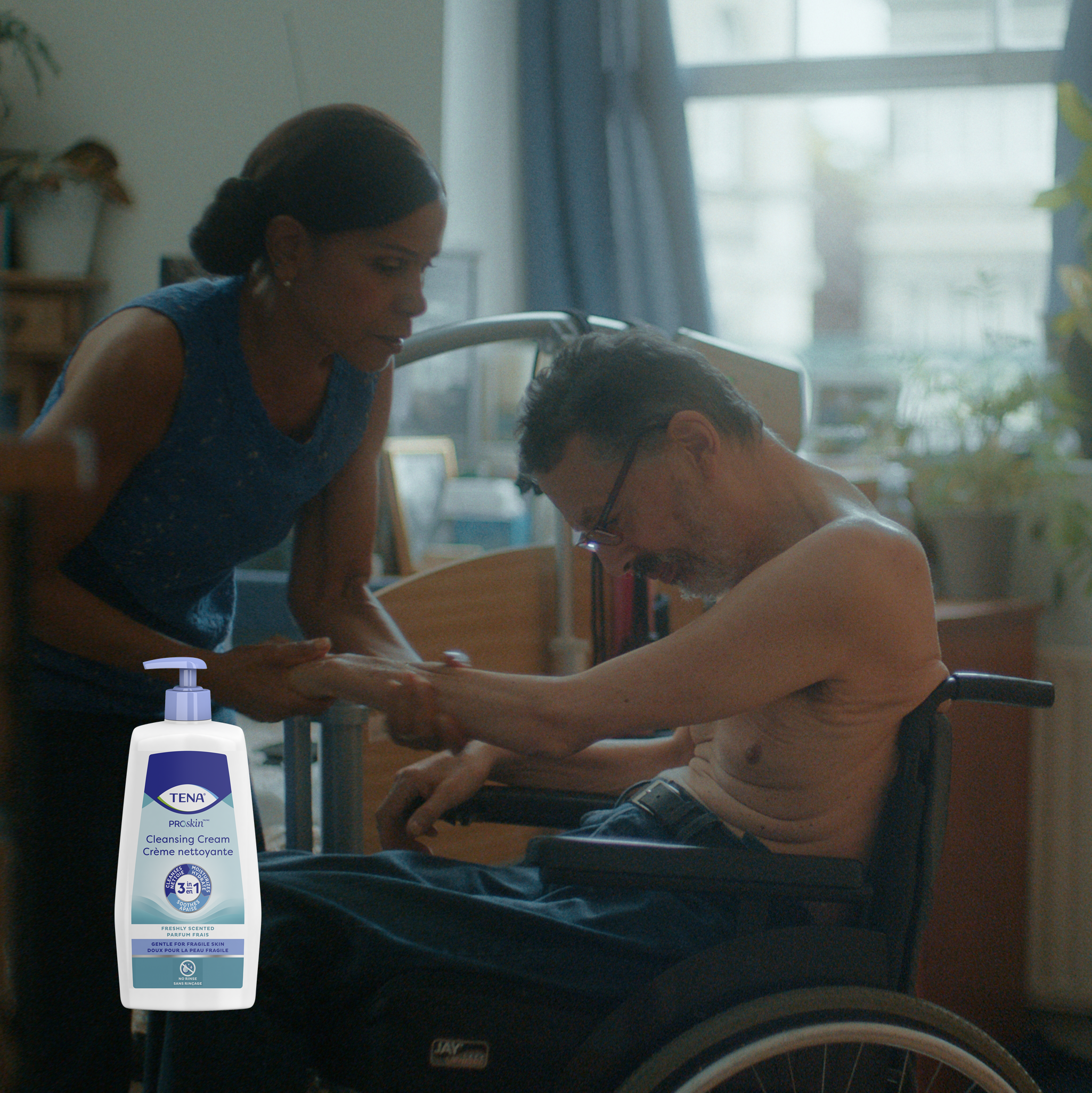 A woman applies lotion to the upper body of her husband, in a wheelchair. A woman applies lotion to the upper body of her husband, in a wheelchair.